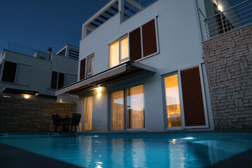 a house with a swimming pool at night at TI Amo Holiday House - Heated Pool in Kaštela
