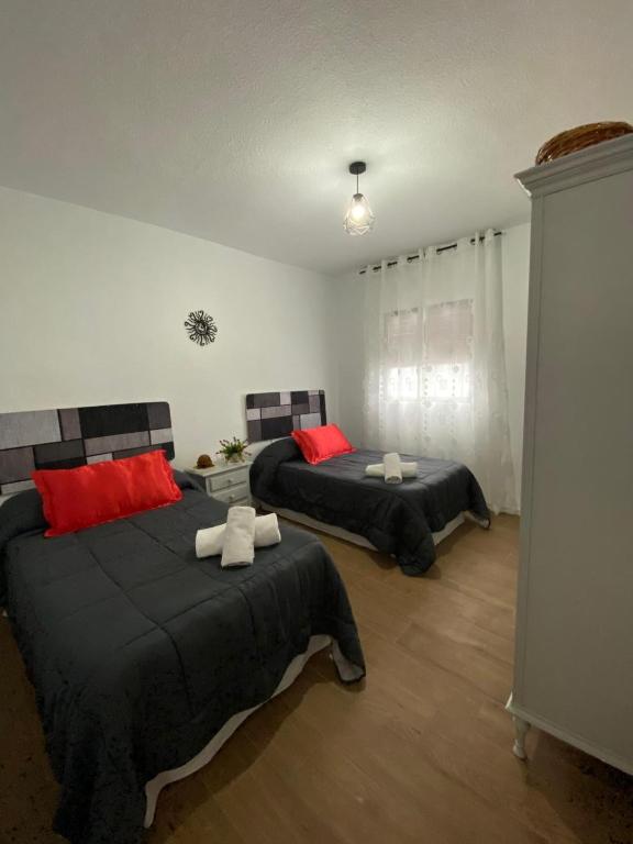 a bedroom with two beds with red pillows at Casa Rural Maria in Pinos Genil