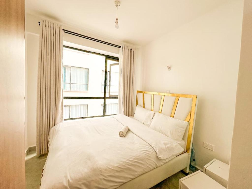 een slaapkamer met een wit bed met een raam bij tsavo roysambu in Nairobi