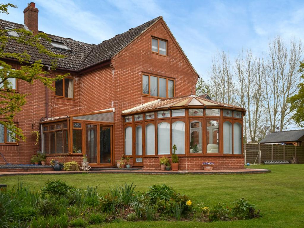 a brick house with a conservatory in the yard at Swallowdale in Flordon