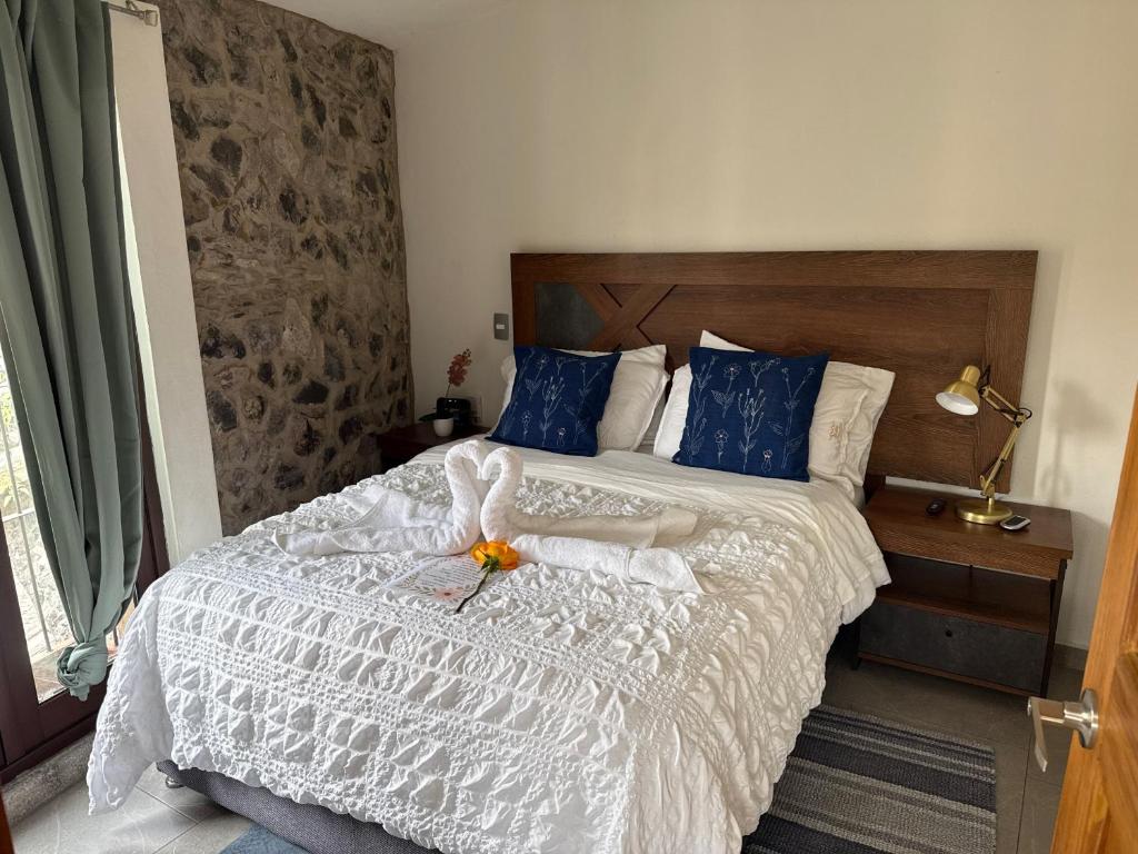 een slaapkamer met een wit bed met blauwe kussens bij Sicilia con Terraza y chimenea in Santeagueda