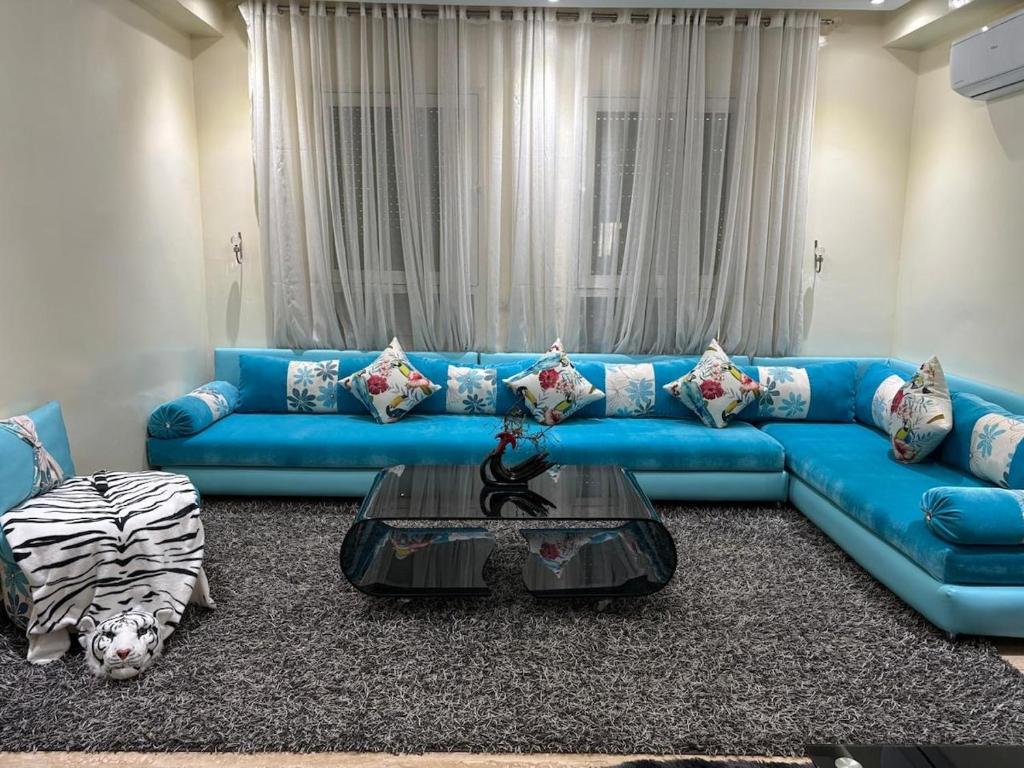 a blue couch in a living room with a table at Appartement Haut Standing in El Jadida