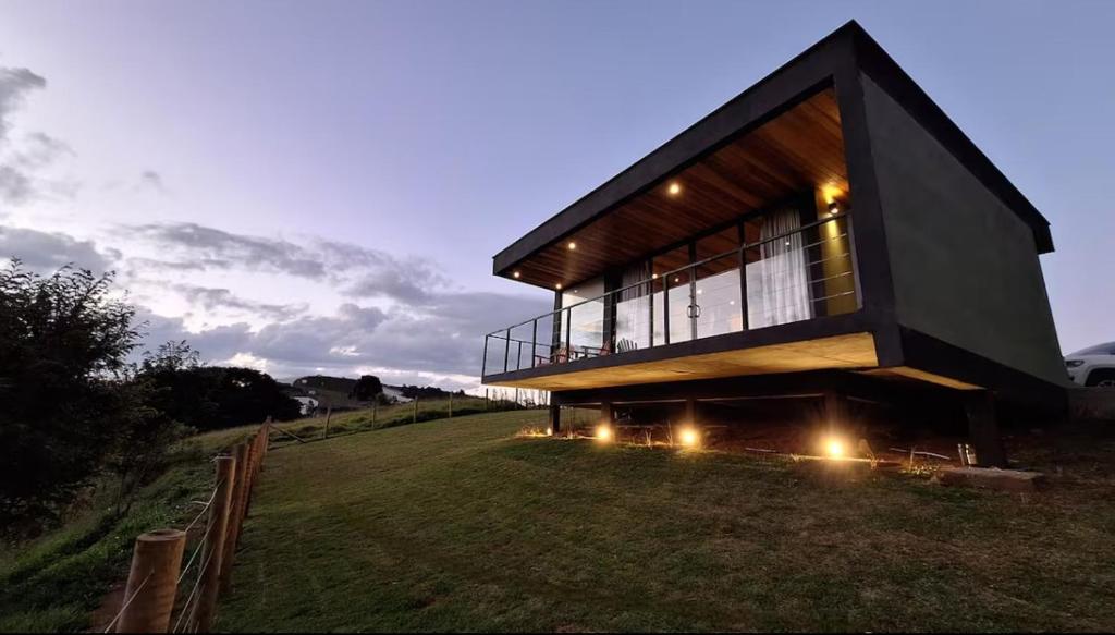 una casa en una colina con luces en un campo en Cabanas 3quedas - Gonçalves-MG, en Gonçalves