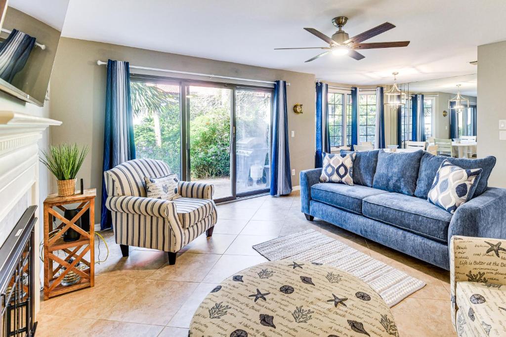 Una sala de estar con un sofá azul y una silla. en Steps to Ocean, Pool Access! Daytona Beach Gem, en Daytona Beach
