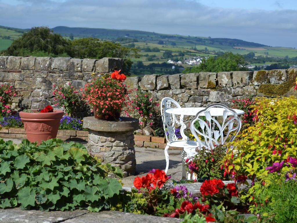 a white bench sitting in a garden with flowers at Rosedale- Lyl in Ireby