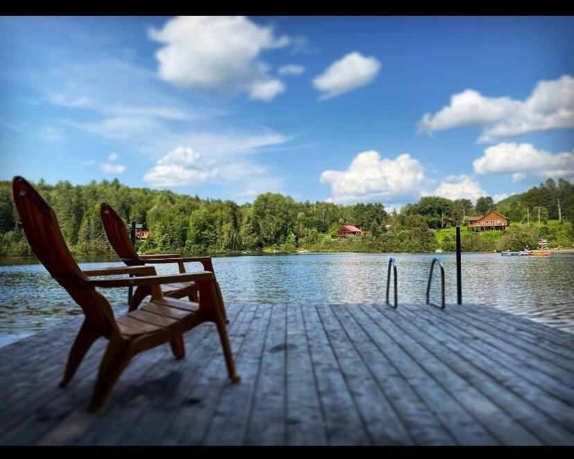 a wooden dock with two chairs sitting on top of a lake at Relax On the Lake Waterfront with Hot Tub in Chertsey