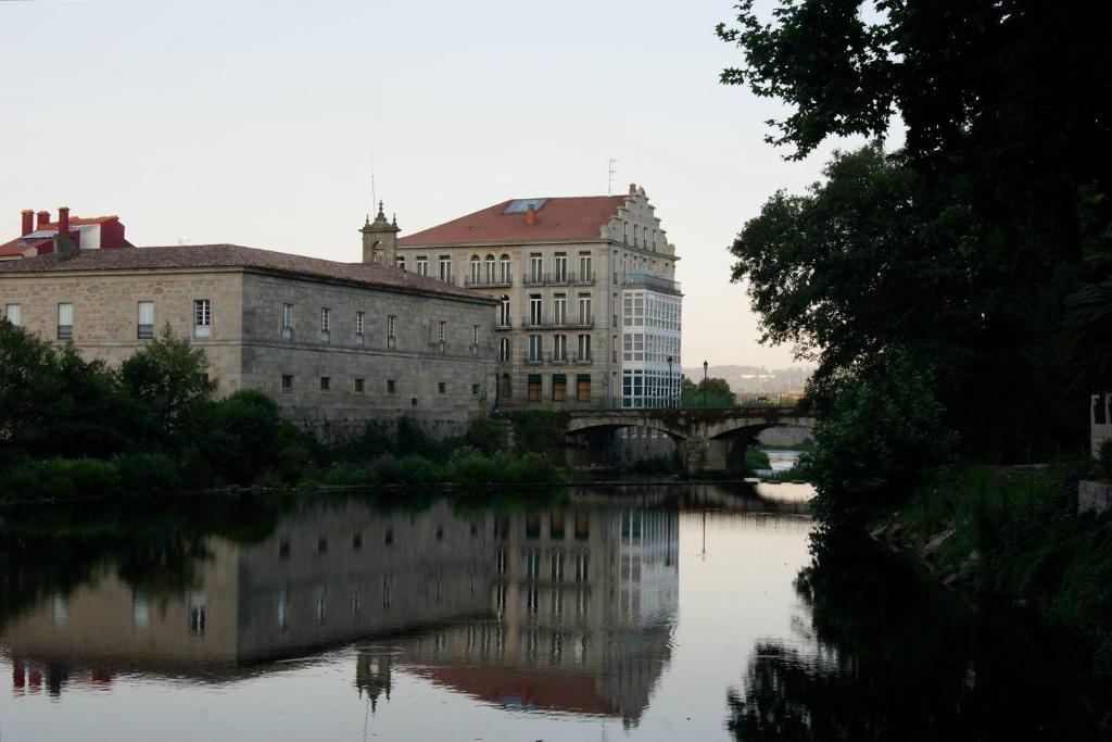 widok na rzekę z budynkami i mostem w obiekcie Balneario Acuña w mieście Caldas de Reis