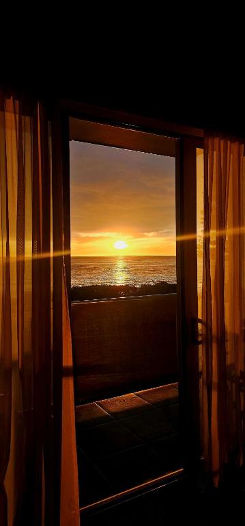 a window with a view of the ocean at sunset at Waves Kaikoura Waterfront Apartment #1 in Kaikoura