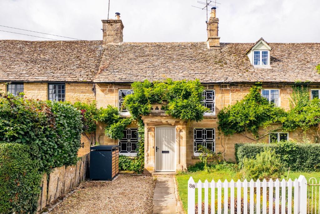 an old stone house with a white fence at Historic 3 Bedroom Cottage in the Cotswolds in Idbury