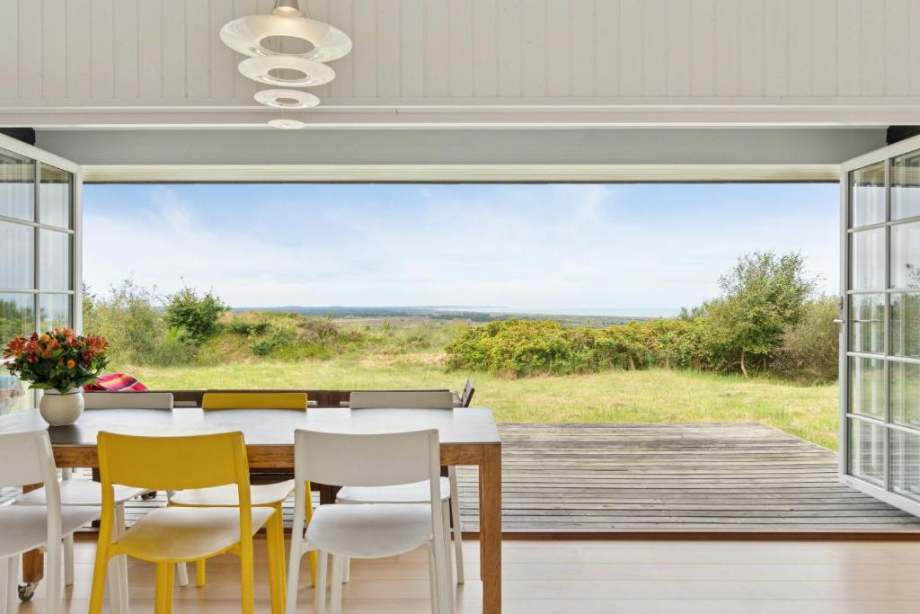 a dining room with a table and chairs and a large window at Family House With Sea View In Svinkløv in Andrup