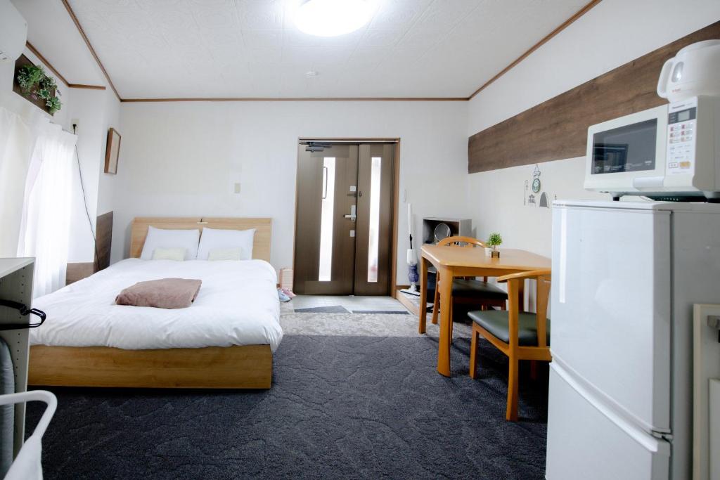 1 dormitorio con cama, escritorio y nevera en Fushimi Railway House, en Kioto