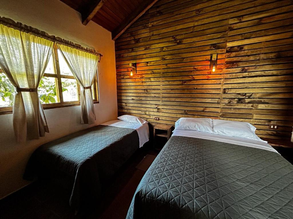 Un dormitorio con dos camas y una pared de madera. en Cabaña Xamixkali, en Zacatlán