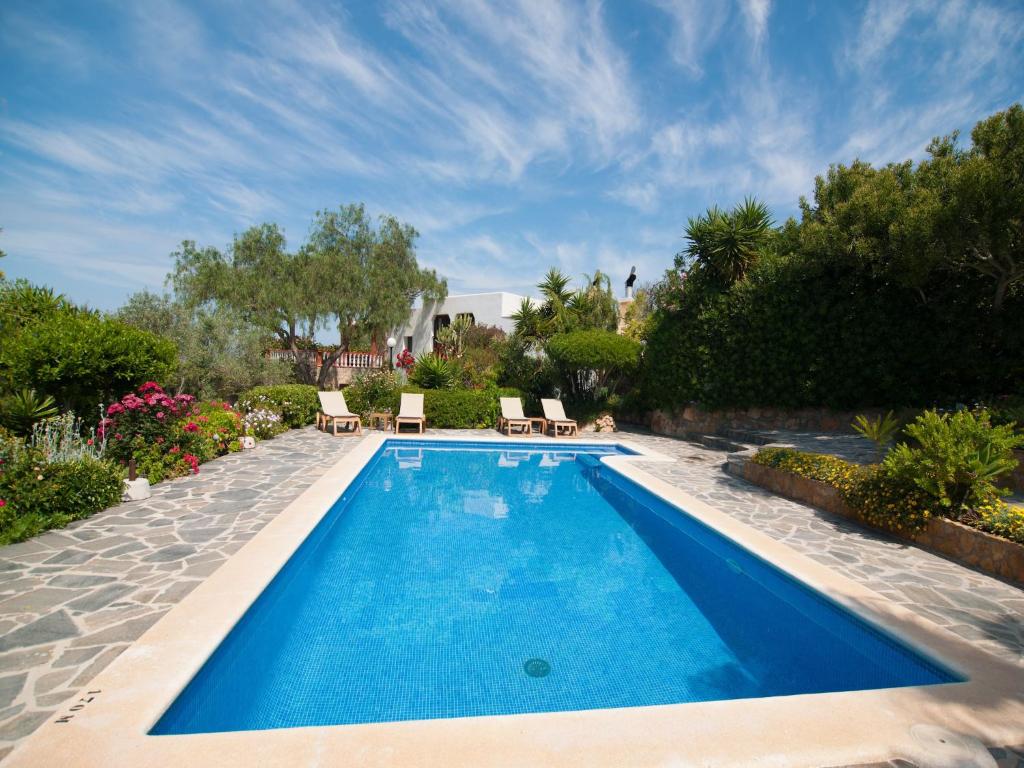a swimming pool in a yard with chairs and flowers at Stylish Ibiza Villa with Pool in Ses Paisses