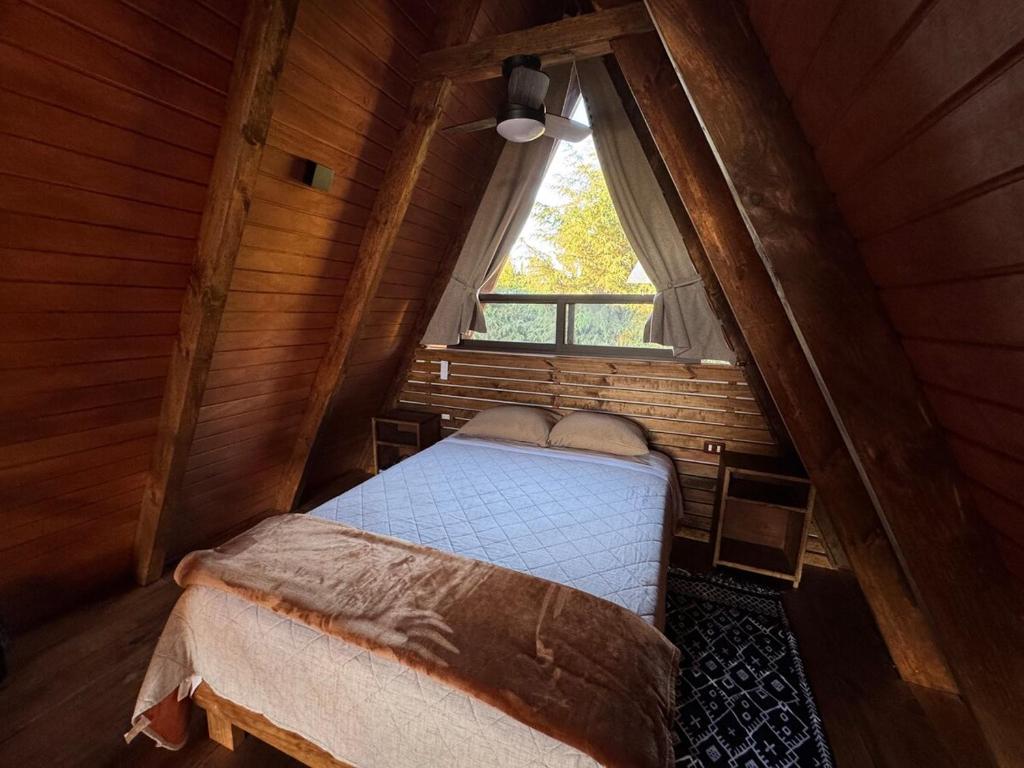 a bedroom in a log cabin with a window at Cabaña Tlazocalli in Zacatlán