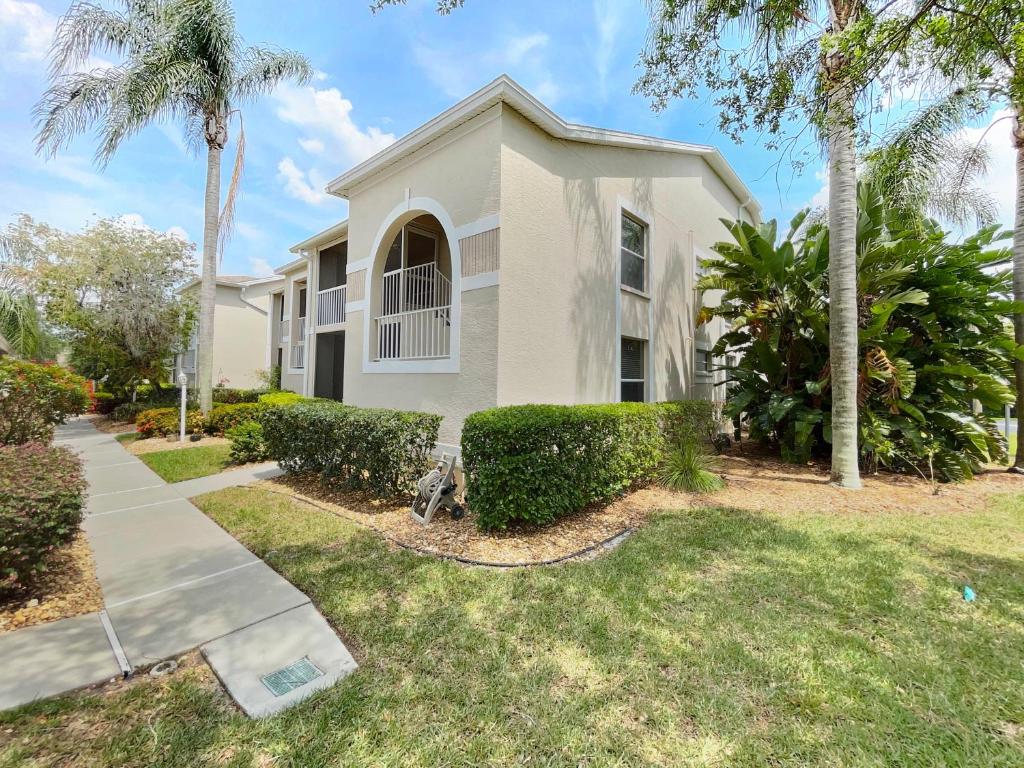 a white house with palm trees and a sidewalk at Stoneybrook Condo #926 in Sarasota