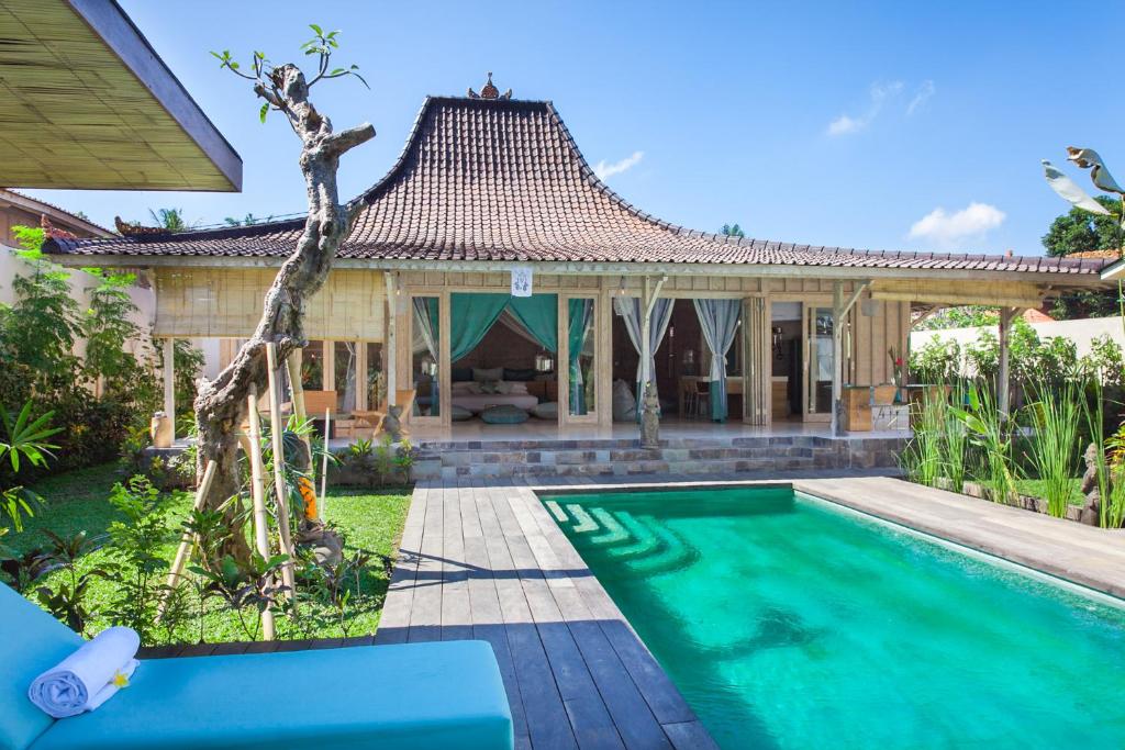 a villa with a swimming pool in front of a house at Mana Sari in Ubud