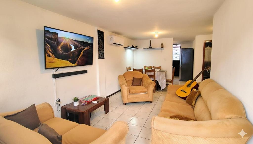 a living room with a couch and a guitar at Acogedora Casa Completa con jacuzzi privado in Quito