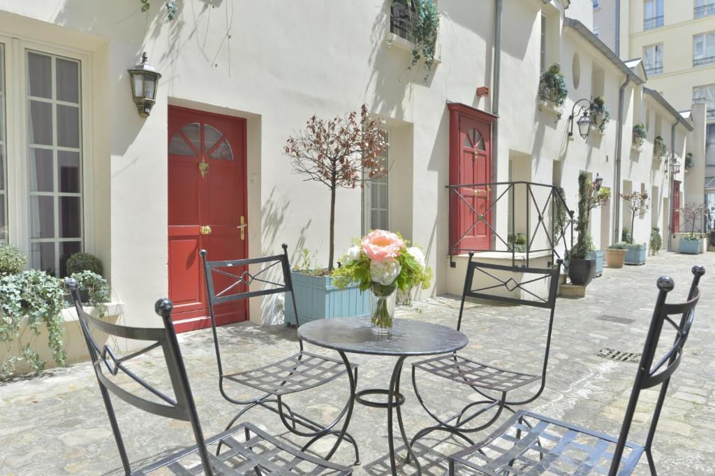 ein Tisch und Stühle mit einer Blumenvase drauf in der Unterkunft Hotel Suites Unic Renoir Saint-Germain in Paris