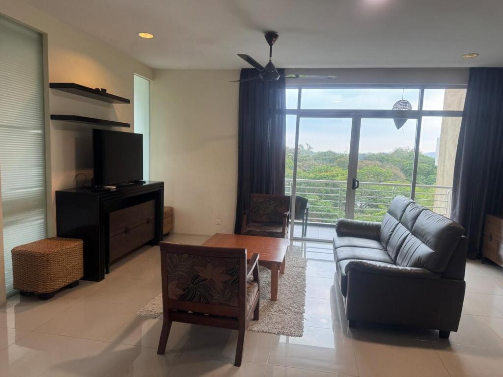 una sala de estar con un sofá y una mesa en Executive Apartment at Cinta Sayang Club, en Sungai Petani