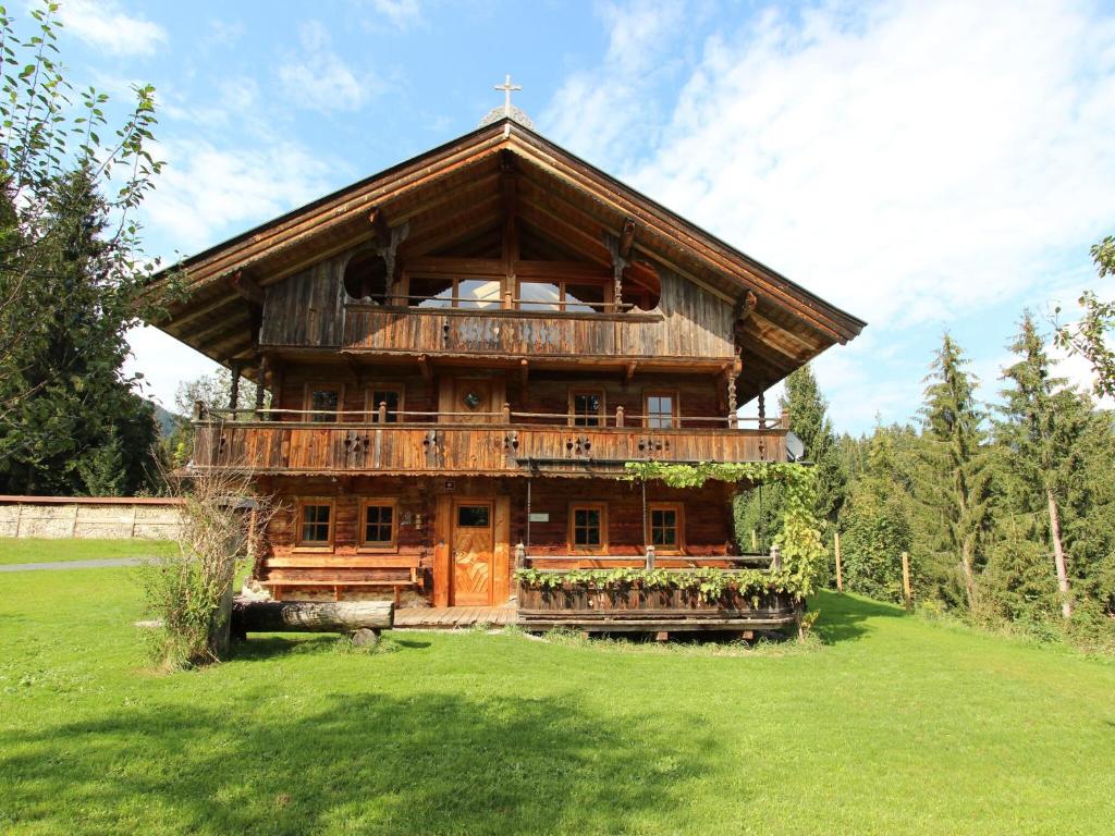 a large wooden building with a balcony in a field at Farmhouse in Hopfgarten near SkiWelt in Hopfgarten im Brixental