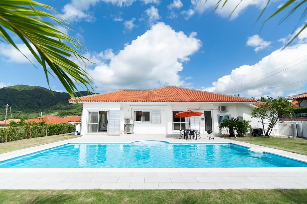 a villa with a swimming pool in front of a house at Sommelier Villa ISHIGAKI - 大型プライベートプール完備のプライベート空間 BBQ可 in Ishigaki Island