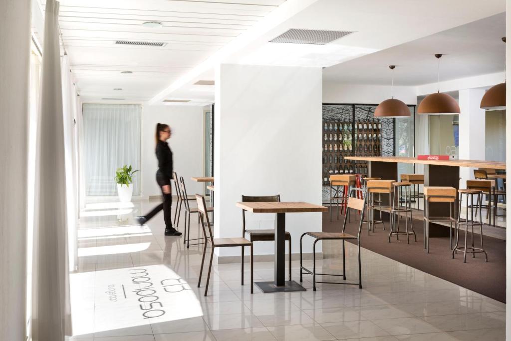 a woman walking through a room with tables and chairs at Hotel San Teodoro in San Teodoro