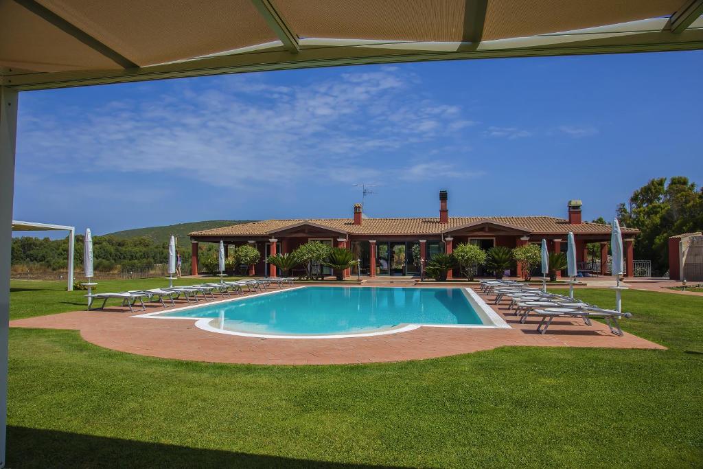 a swimming pool with chairs and a house at Villa Barbarina Nature Resort in Santa Maria la Palma