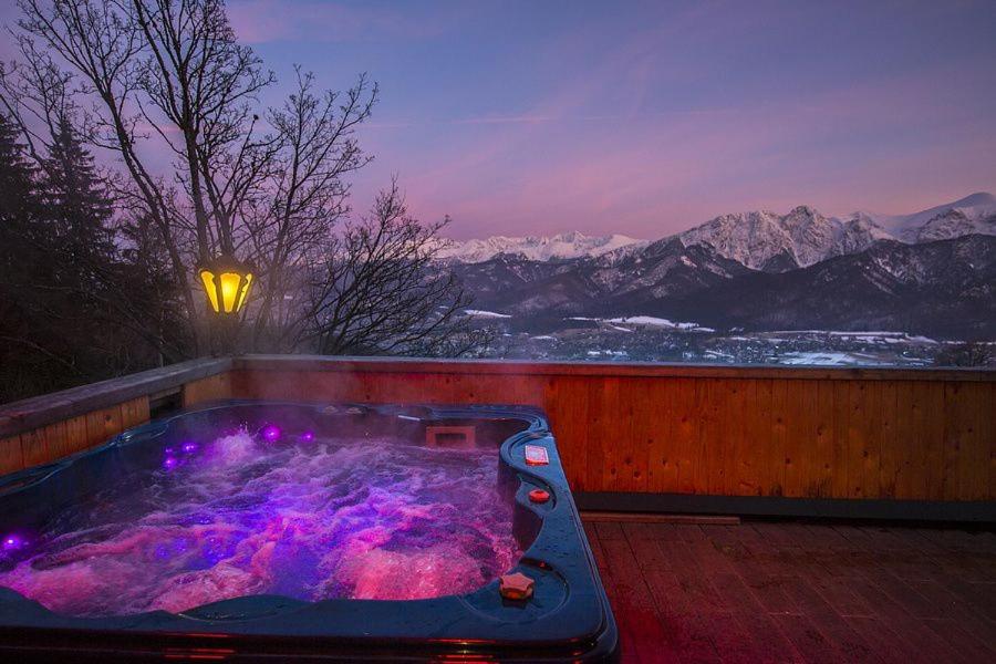 a hot tub on a deck with a view of mountains at Willa Irena in Kościelisko