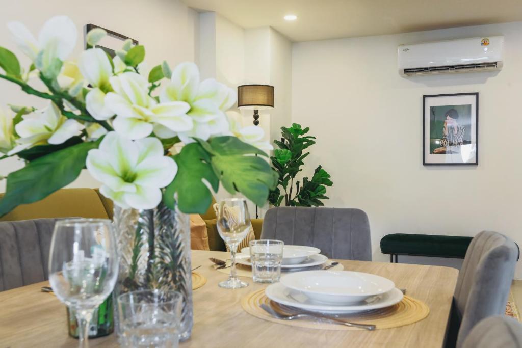 ein Esstisch mit einer Vase mit weißen Blumen in der Unterkunft Wink Hill 1 Penthouse Patong 4 Bedrooms in Patong Beach