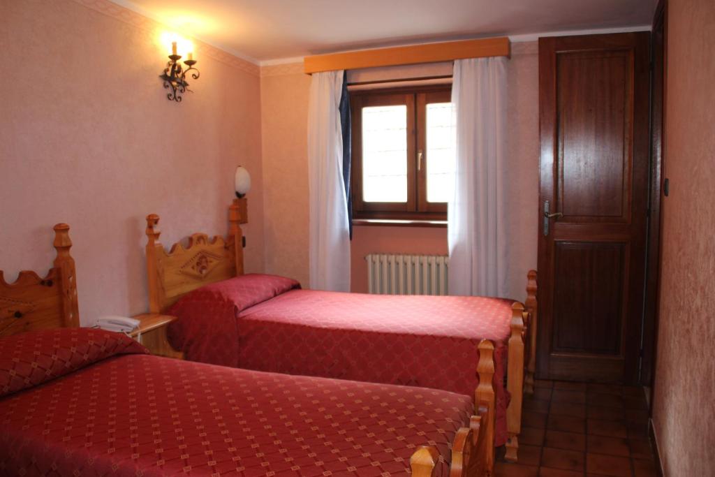 a small bedroom with two beds and a window at Hotel Banchetta in Sestriere