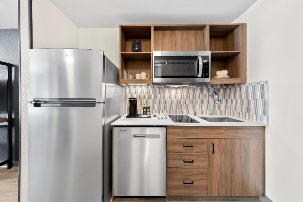 a kitchen with a stainless steel refrigerator and a microwave at Everhome Suites San Bernardino - Loma Linda in San Bernardino