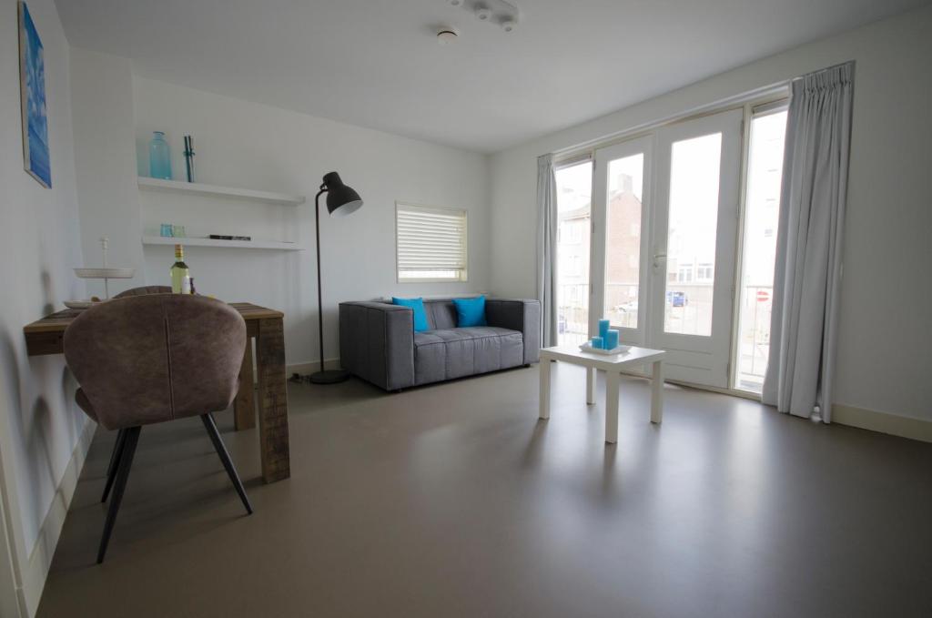 a living room with a chair and a desk and a couch at Flamingo Beach Apartments in Zandvoort