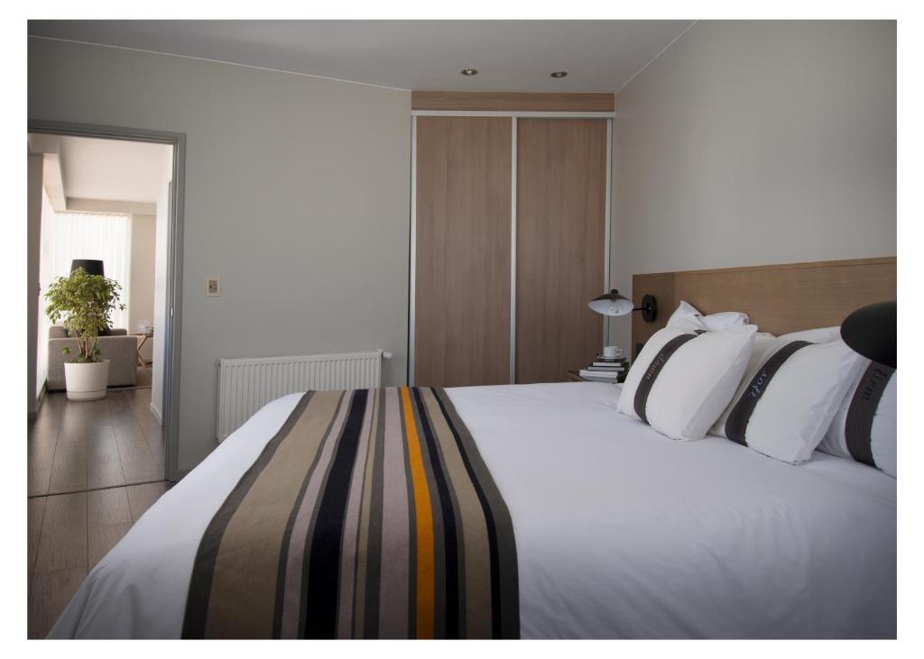 una camera da letto con un grande letto bianco con cuscini bianchi di Casa Grande Suites a La Paz