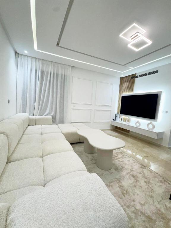 马拉喀什Appartement de Luxe 3 Chambres avec piscine au centre的客厅里有一张白色沙发和一台电视
