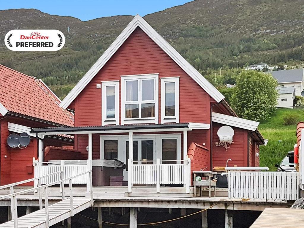 a red house with a deck and mountains in the background at 6 person holiday home in Gursken-By Traum in Larsnes