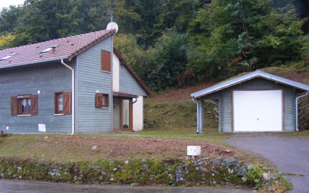 a blue house with a white door and a garage at le chalet in Saint-Nabord