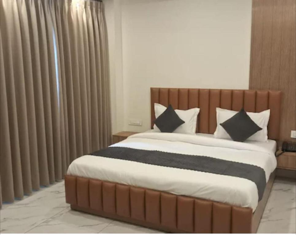 a bedroom with a large bed with black and white pillows at Hotel Anji Solan Hills in Solan