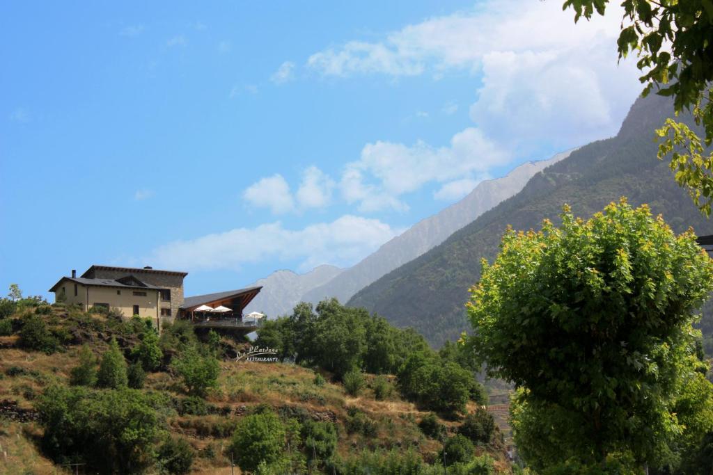 uma casa numa colina com montanhas ao fundo em La Llardana em Benasque