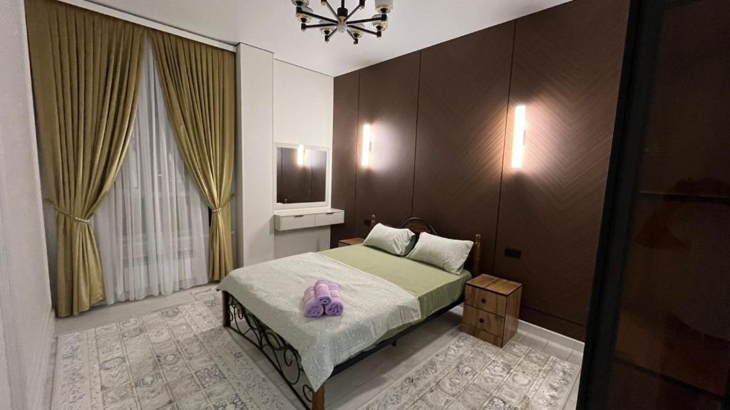 ein Schlafzimmer mit einem Bett mit einem lila Kissen darauf in der Unterkunft Шикарная 2х комнатная квартира ЖК БИРЛИК in Schymkent