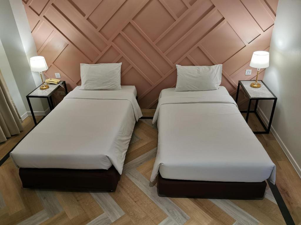 two beds in a small room with two lamps at The Regent Ubon in Ubon Ratchathani