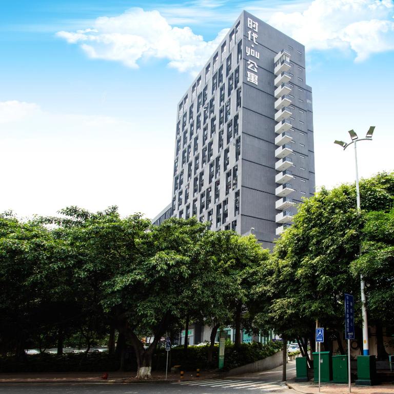 un edificio alto con árboles delante de él en Nuomo Times You Apartment, en Guangzhou
