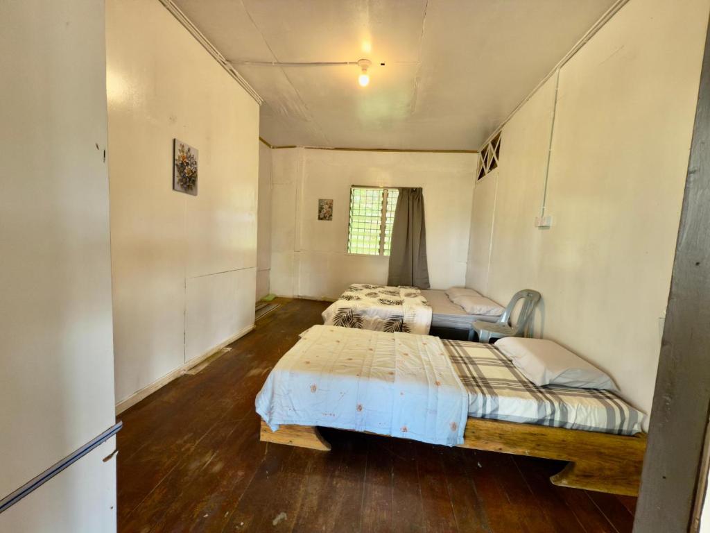 two beds in a room with wooden floors at Rustic Bed & Breakfast in Ranau