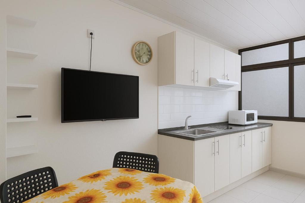 a kitchen with a table and a tv on the wall at Apartamento con jardín y pequeña piscina privada para refrescarse in Maspalomas