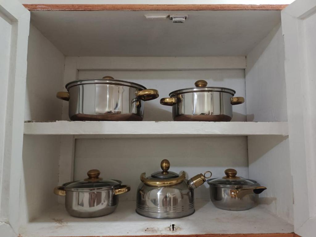 three pots and pans on shelves in a kitchen at Laika the Beagle's Home away from Home - Clark in Angeles