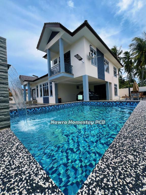 a house with a swimming pool in front of a house at Nawra Homestay PCB in Kota Bharu