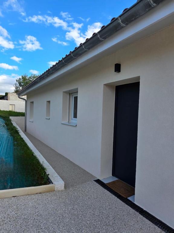a white building with a door next to a pool at Gîte le Brahmã in Châteauneuf-sur-Isère