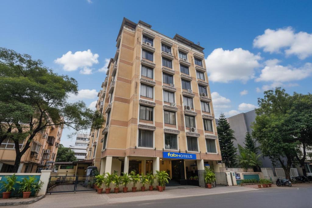 a tall tan building with a blue sign on it at FabHotel Olive Suite - Near Airforce get in Pune