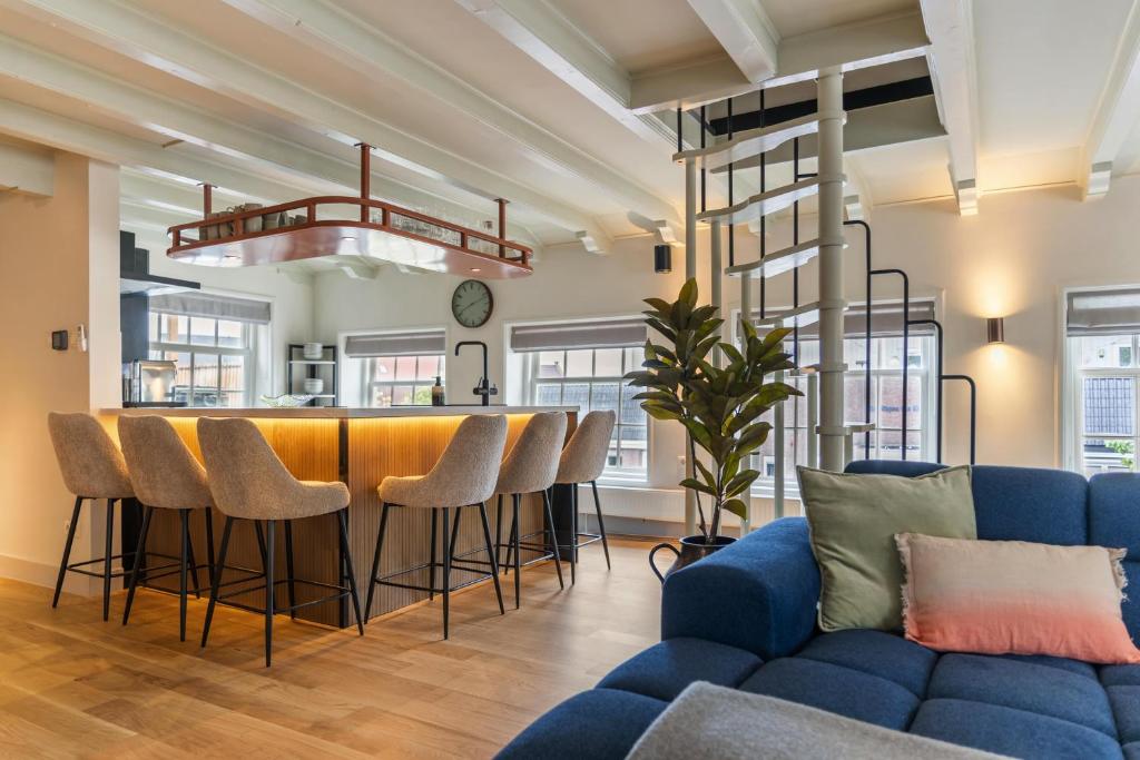 a living room with a blue couch and a bar at Luxury Harbour Apartment with Sauna and Jacuzzi in Medemblik