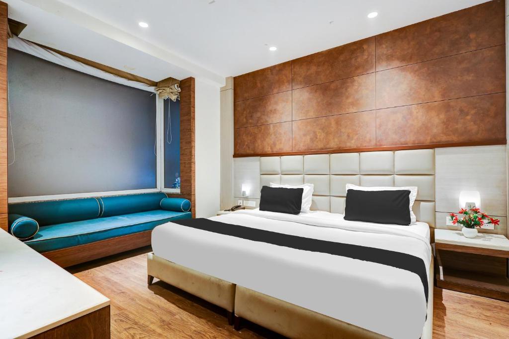 une chambre avec un grand lit et un canapé bleu dans l'établissement Super Townhouse Chhatarpur Near Metro Park, à Jāmb