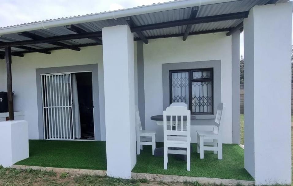 un patio con mesa y sillas bajo una pérgola en Catalina Bay Beach Retreat - Dolphin Inn, en Hibberdene